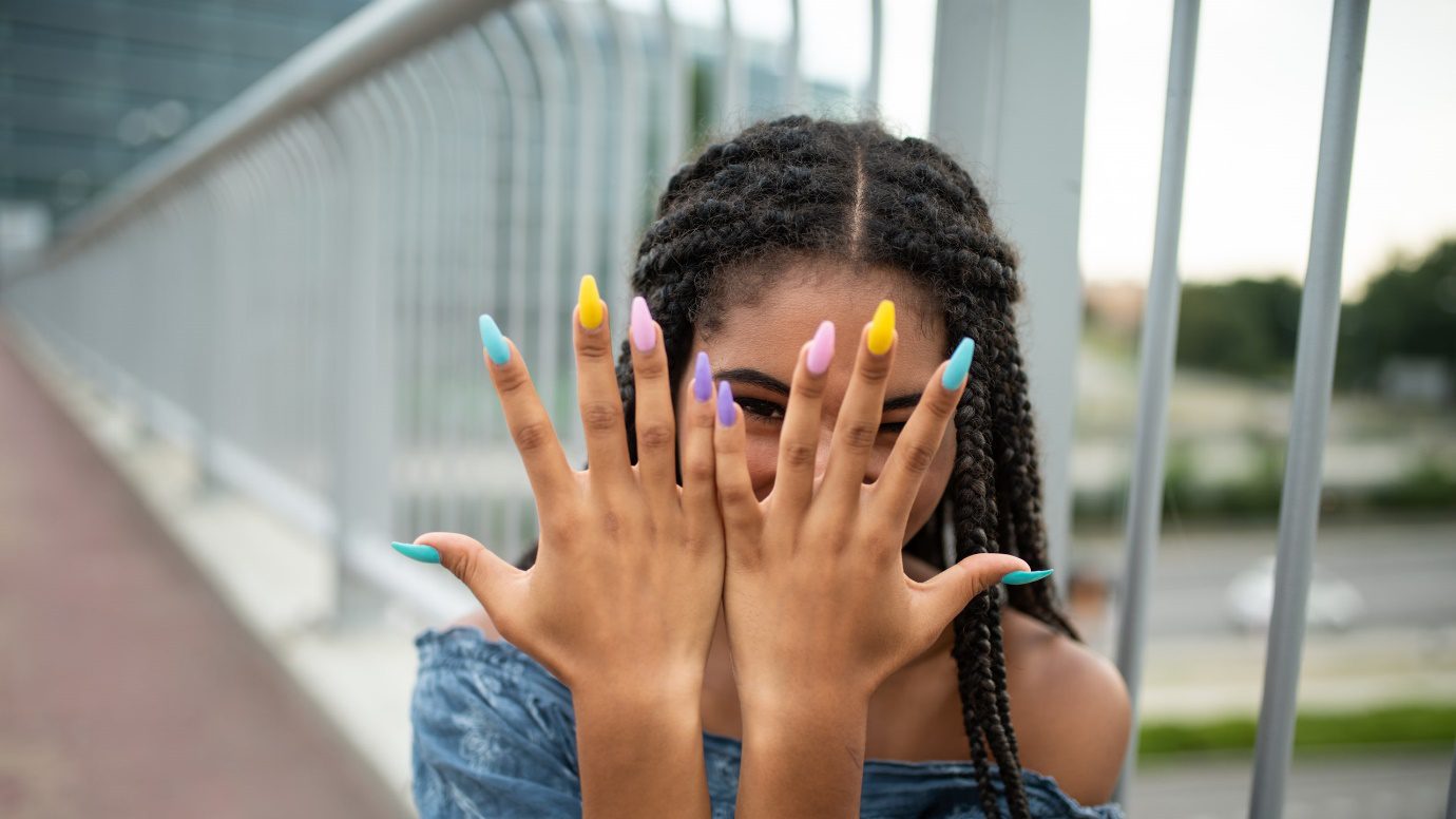 Teen showcasing multicolored long nails fashion lifestyle concept.
